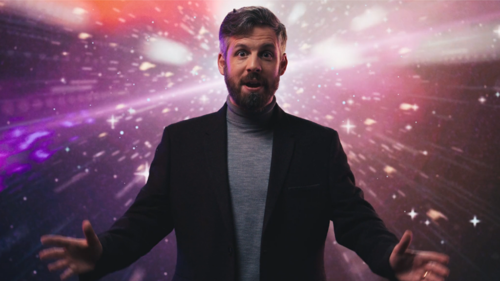 man stood centre frame in front of galaxy LED screen