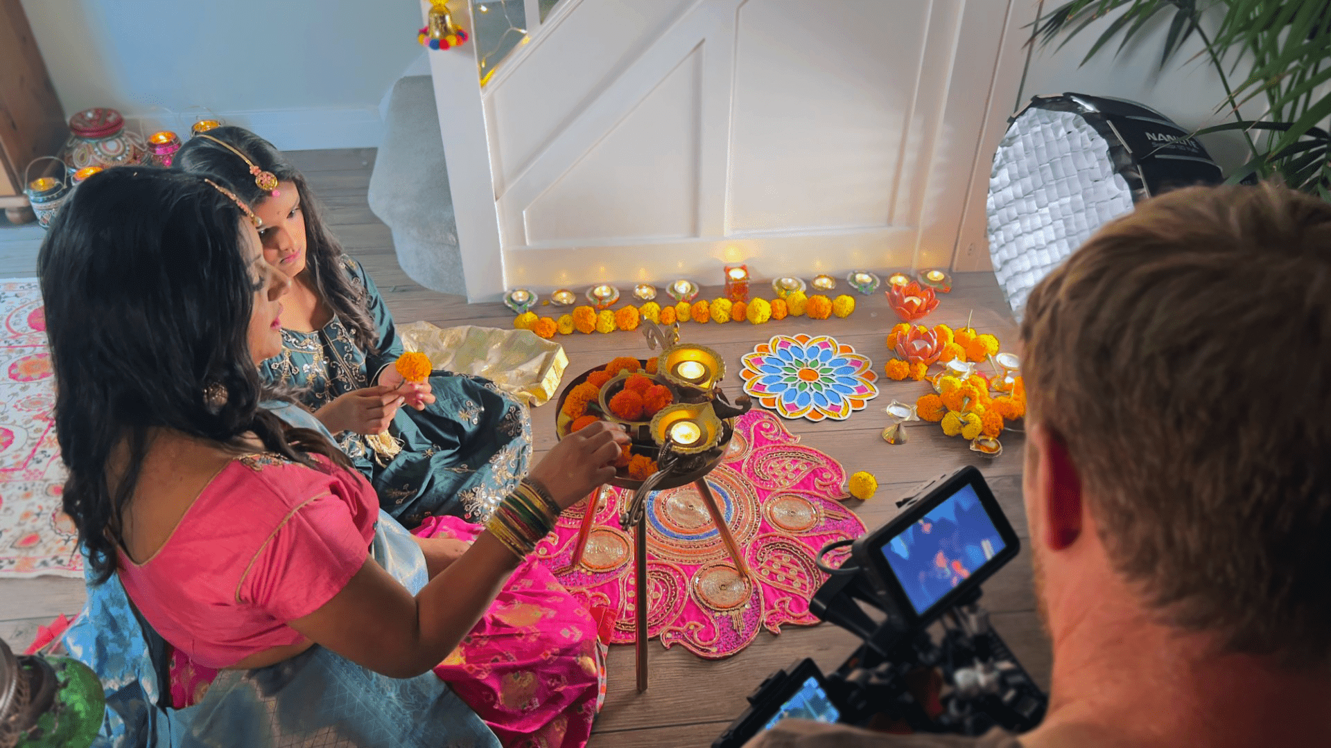 image of a video production set and a camera filming a mother and daughter lighting a lamp